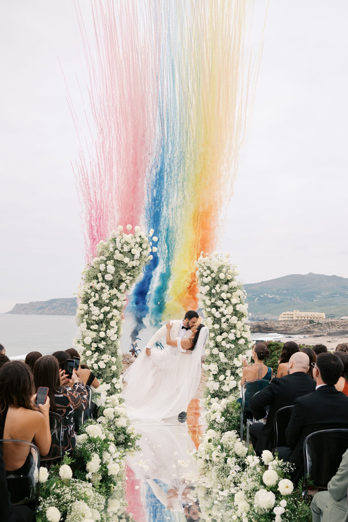 Cerimónia à beira-mar com fumo colorido a preencher o arco floral